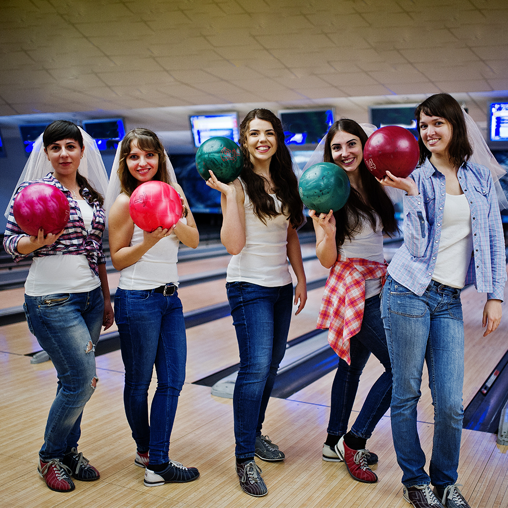 Group of six girls wit bowling balls at hen party on bowling club